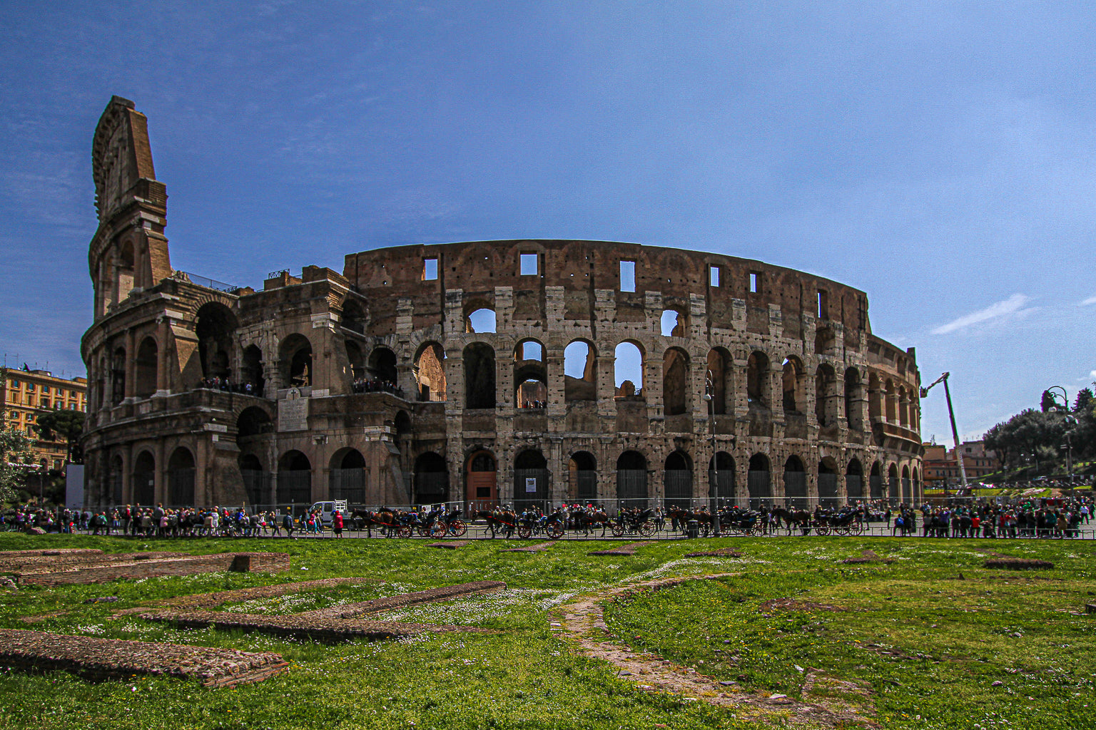 The Colosseum in Rome under a clear blue sky with visitors.