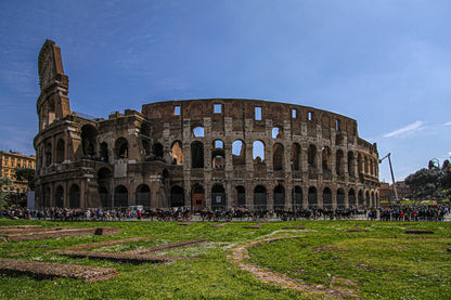 The Colosseum in Rome under a clear blue sky with visitors.