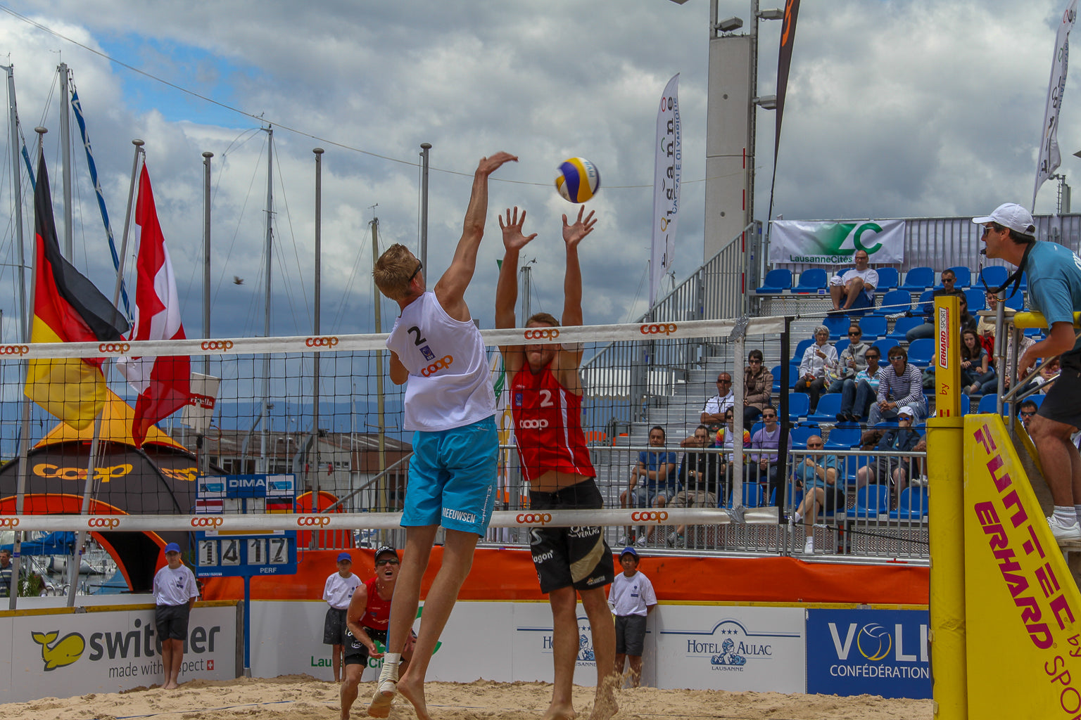 Beach volleyball players jumping at the net during a match.