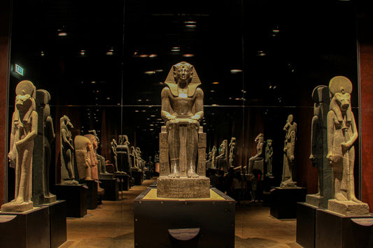 Museum gallery with a central seated statue and rows of sculptures.