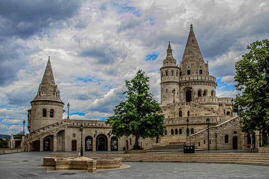 Historic stone towers and arches in a courtyard beneath a dramatic, cloud-filled sky.