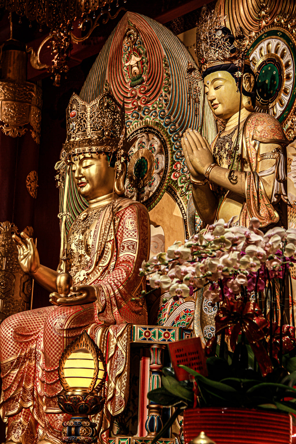 Ornate temple statues and golden décor illuminated in warm interior light.