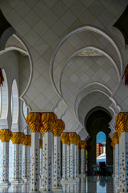 Repeating white arches and gold capitals in a symmetrical architectural corridor.