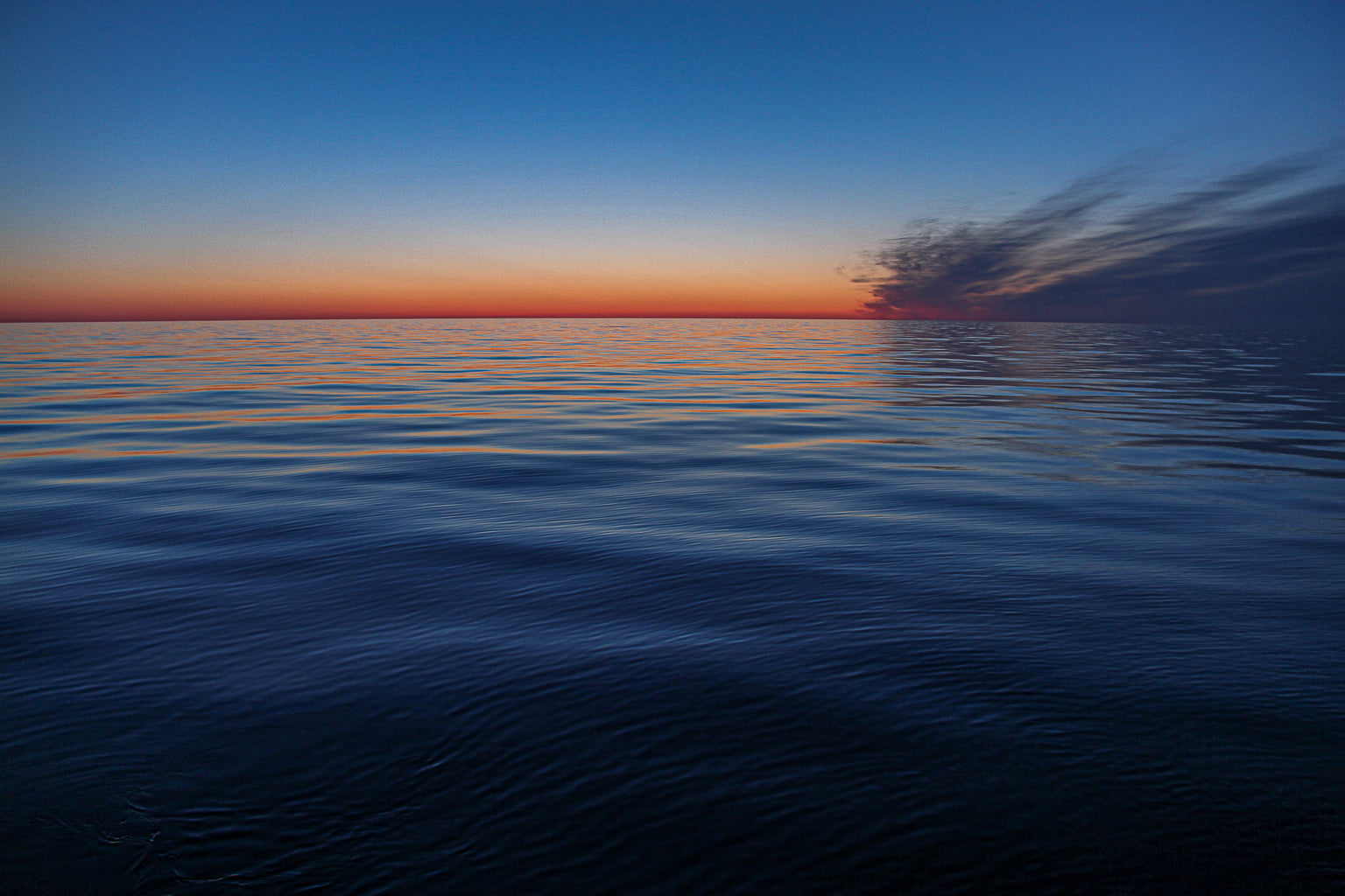 Minimal ocean horizon at sunset with motion-blurred water.