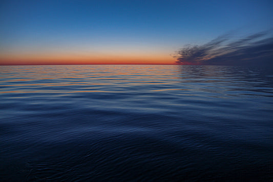 Minimal ocean horizon at sunset with motion-blurred water.